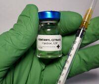 Close-up of a gloved hand holding a vial of Fentanyl Citrate injection and a syringe, highlighting the potent opioid's medical use and addiction risks