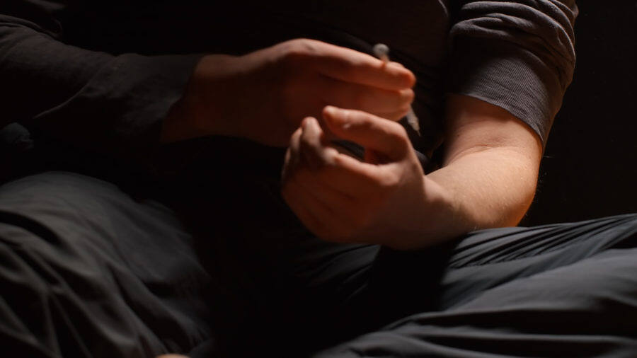 Close-up of hands preparing heroin for injection, highlighting the dangers and urgency of addressing heroin addiction