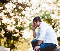 Man sitting outdoors, head in hand, reflecting on cocaine addiction and the path to recovery