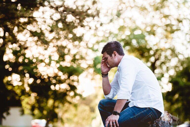 Man sitting outdoors, head in hand, reflecting on cocaine addiction and the path to recovery