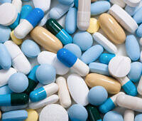 Close-up of various colorful prescription pills and capsules including blue, white, yellow, and green medications scattered together