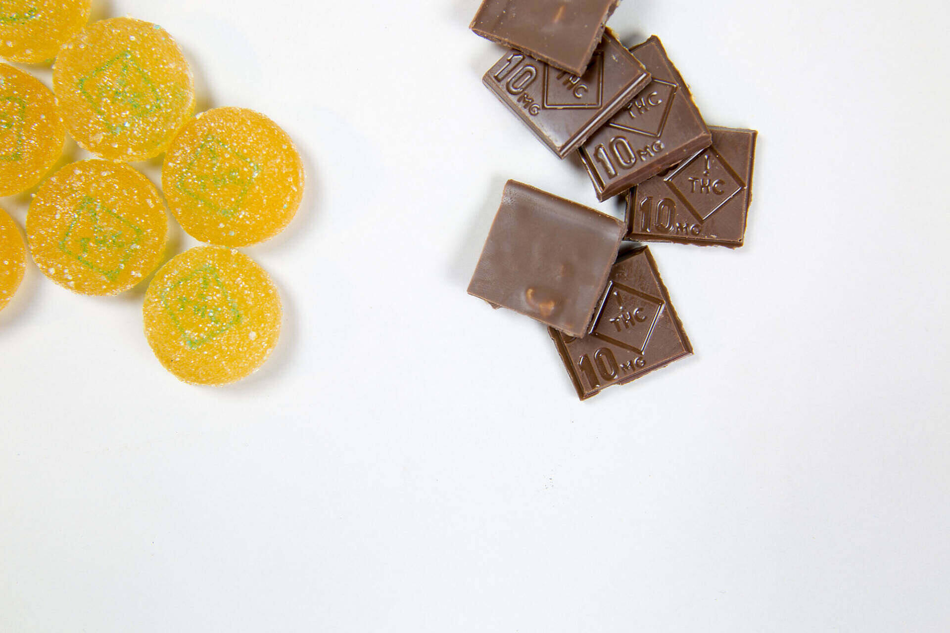 Comparison of cannabis edibles: yellow gummies with sugar crystals and dark chocolate squares marked '10mg'