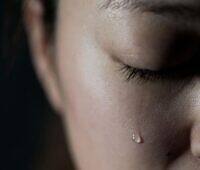 Close-up of a person's face with a single tear, symbolizing the emotional challenges of addiction and recovery