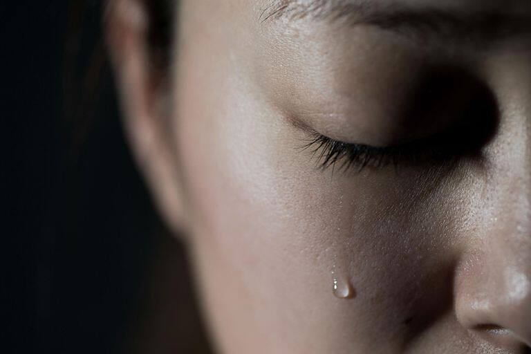 Close-up of a person's face with a single tear, symbolizing the emotional challenges of addiction and recovery