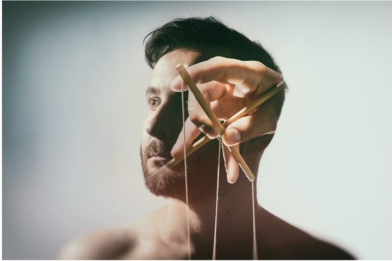 Holding puppet strings in front of a man's face, symbolizing breaking free from addiction and regaining self-control