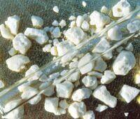 Close-up of crack cocaine rocks scattered on a textured surface with glass tubes, illustrating the appearance and paraphernalia associated with crack cocaine use