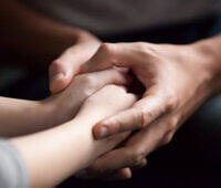 Close-up of hands gently holding and supporting each other, symbolizing care and support in addiction recovery