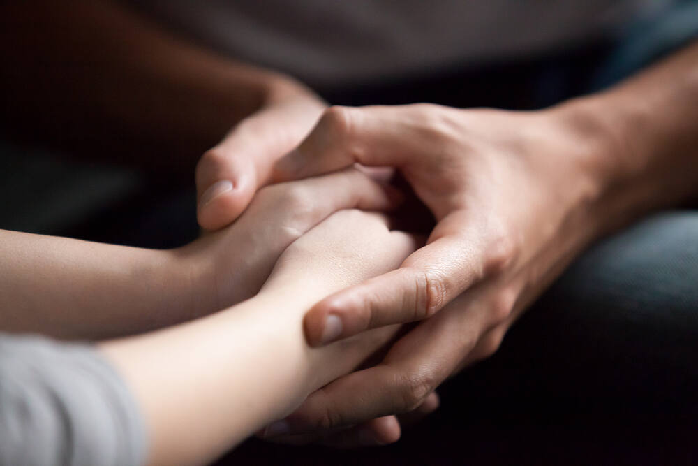 Close-up of hands gently holding and supporting each other, symbolizing care and support in addiction recovery