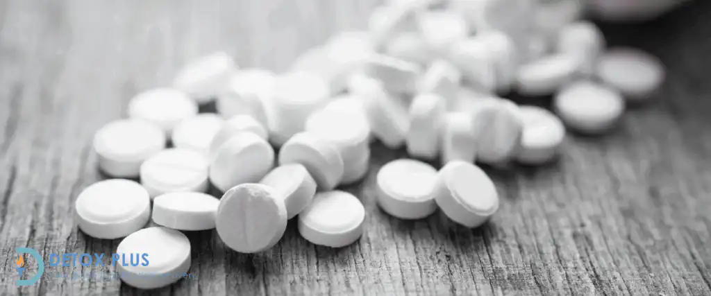 Pile of oxycontin pills spread out on a greyscale wooden table
