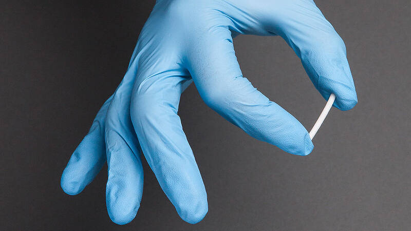 Medical professional's hand in blue glove holding a naltrexone implant for addiction treatment