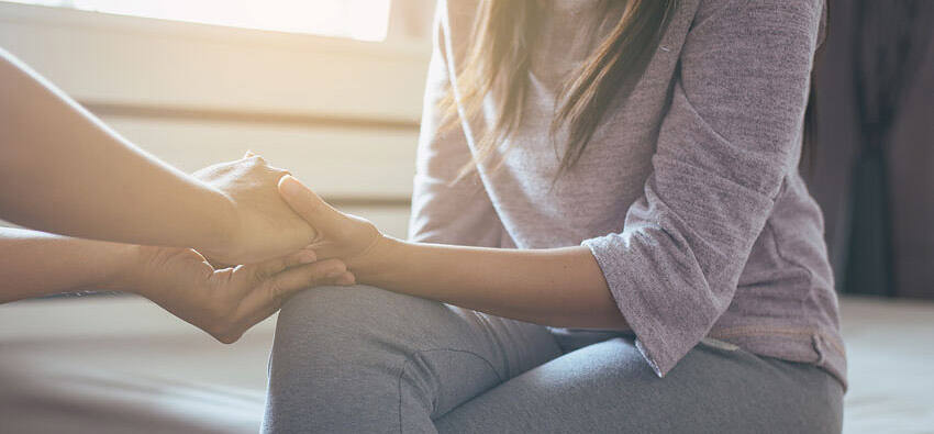 Two people holding hands in a supportive gesture, symbolizing care and support during alcohol rehabilitation