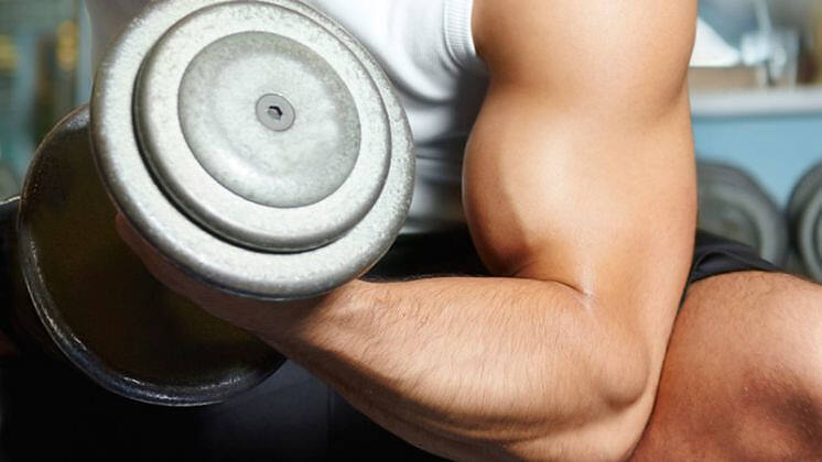 Close-up of a muscular arm lifting a heavy dumbbell, illustrating the effects of anabolic steroid use in bodybuilding and strength training