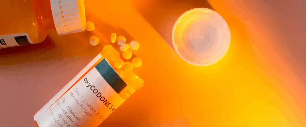 Tub of oxycodone pills on an orange background