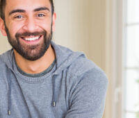 Bearded man in grey hoodie smiling confidently after drug and alcohol rehab treatment