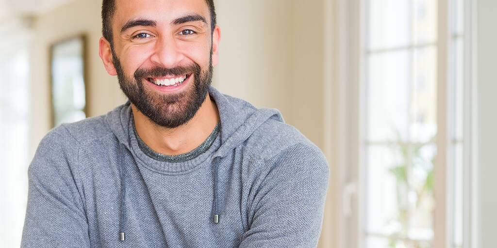 Bearded man in grey hoodie smiling confidently after drug and alcohol rehab treatment