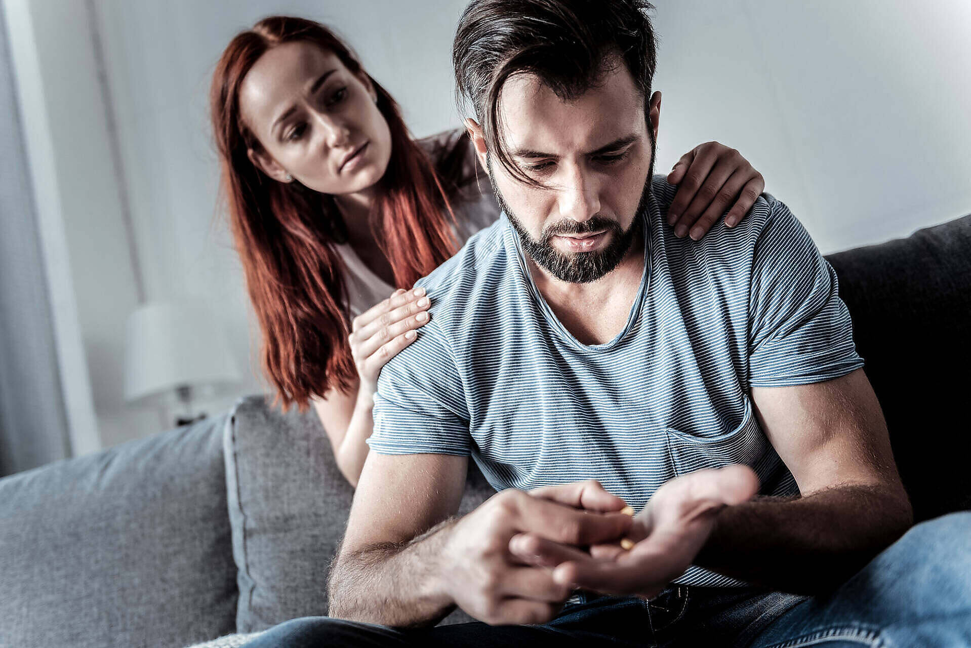 Woman comforting man struggling with cocaine addiction, showing signs of distress and withdrawal