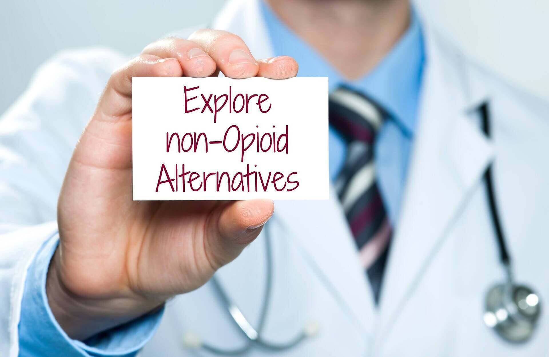 A healthcare professional holding a card that says "Explore non-Opioid Alternatives," emphasizing options for managing pain without morphine or other opioids.