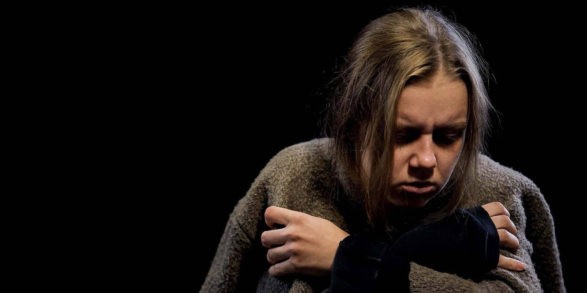 A young woman with a distressed expression, hugging herself while wearing a cozy sweater, illustrating the emotional impact of morphine addiction.