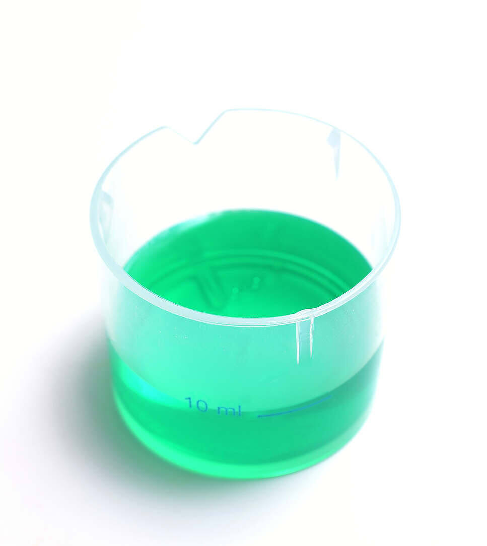 Bright green methadone liquid in a clear 10ml measuring cup, used for addiction treatment