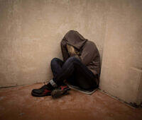 Person in hoodie sitting alone in corner, depicting depression and isolation often associated with addiction