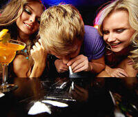 Young people using cocaine at a party, with alcoholic drinks visible, highlighting risks of party drug abuse