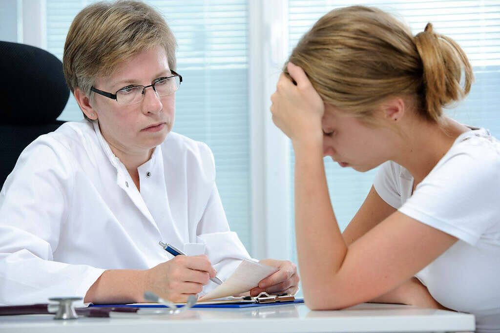 Female doctor consulting with distressed patient about mogadon addiction in medical office