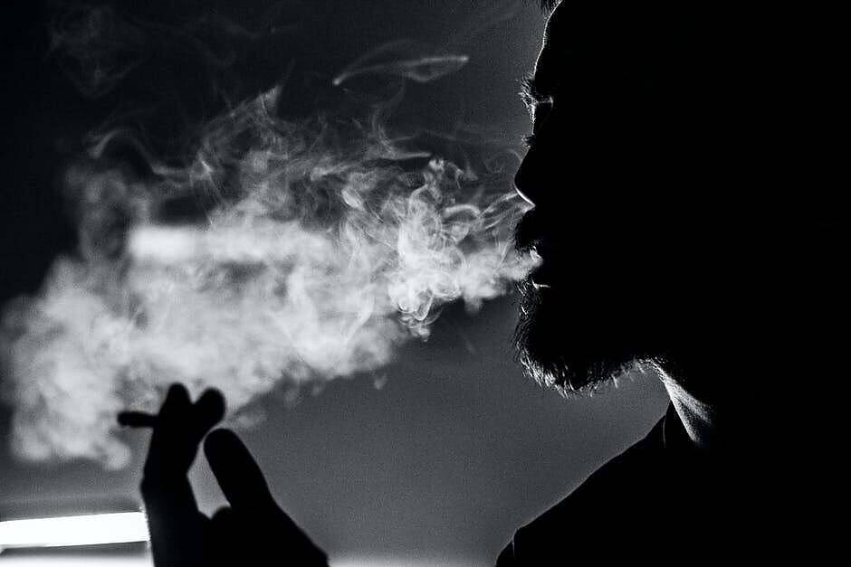 Black and white image of a person's silhouette exhaling a cloud of smoke, illustrating the use of Spice drug