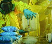 Chemists in yellow hazmat suit handling dangerous chemicals in a makeshift laboratory setting