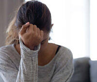 Distressed woman holding her head, showing signs of alcohol withdrawal during detox