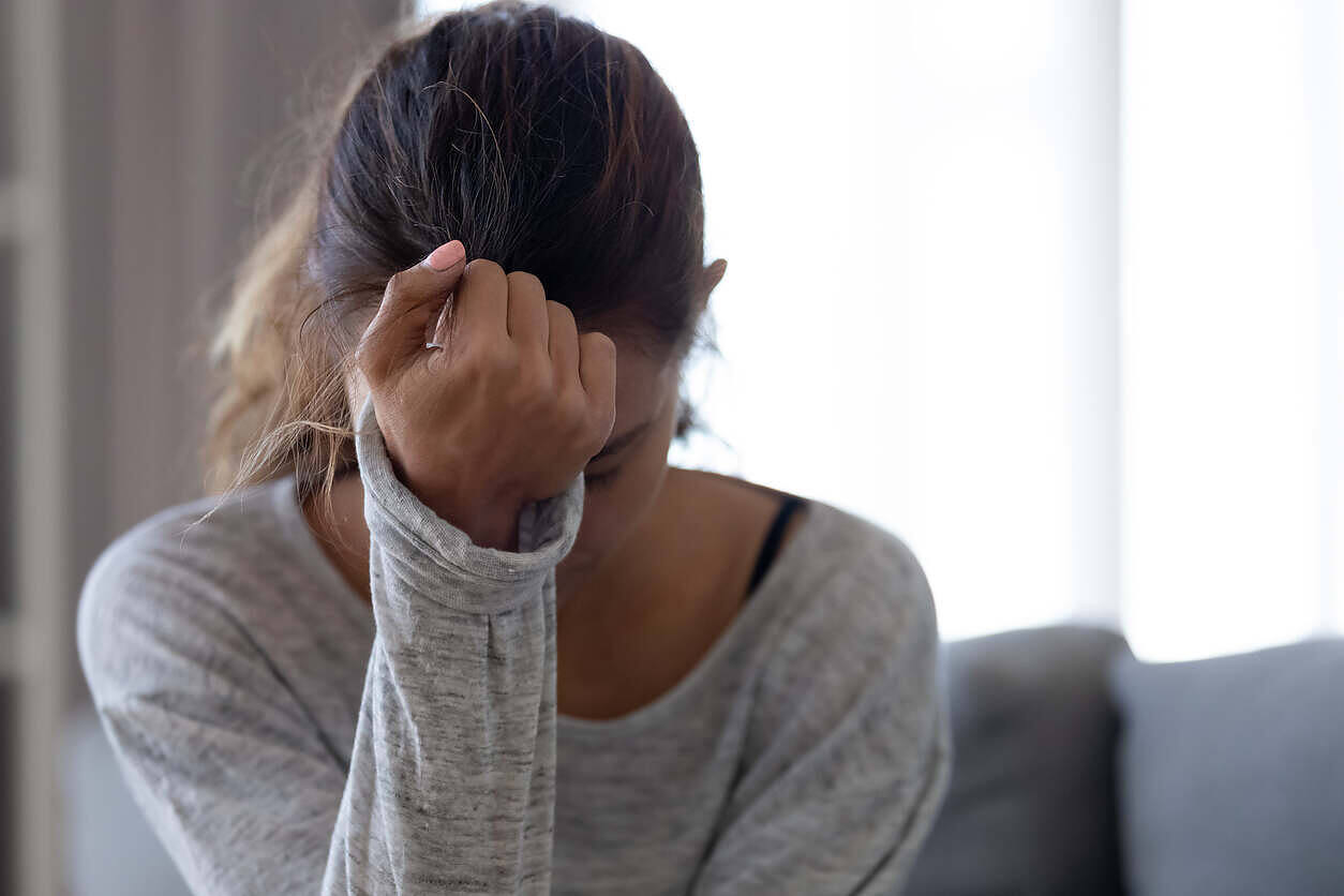 Distressed woman holding her head, showing signs of alcohol withdrawal during detox