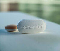 White lorazepam pill with imprint on a light blue surface, illustrating benzodiazepine medication in addiction treatment