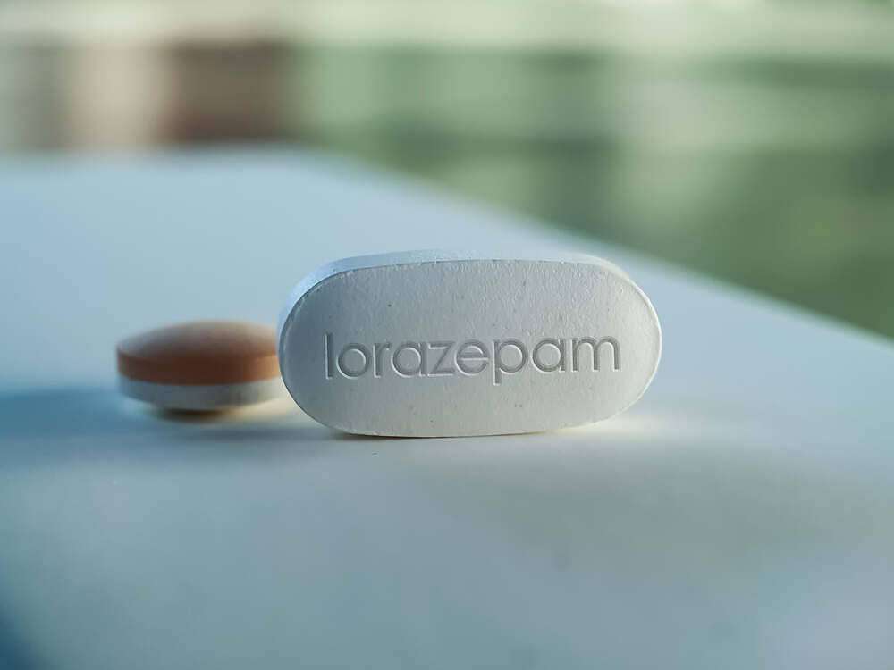 White lorazepam pill with imprint on a light blue surface, illustrating benzodiazepine medication in addiction treatment