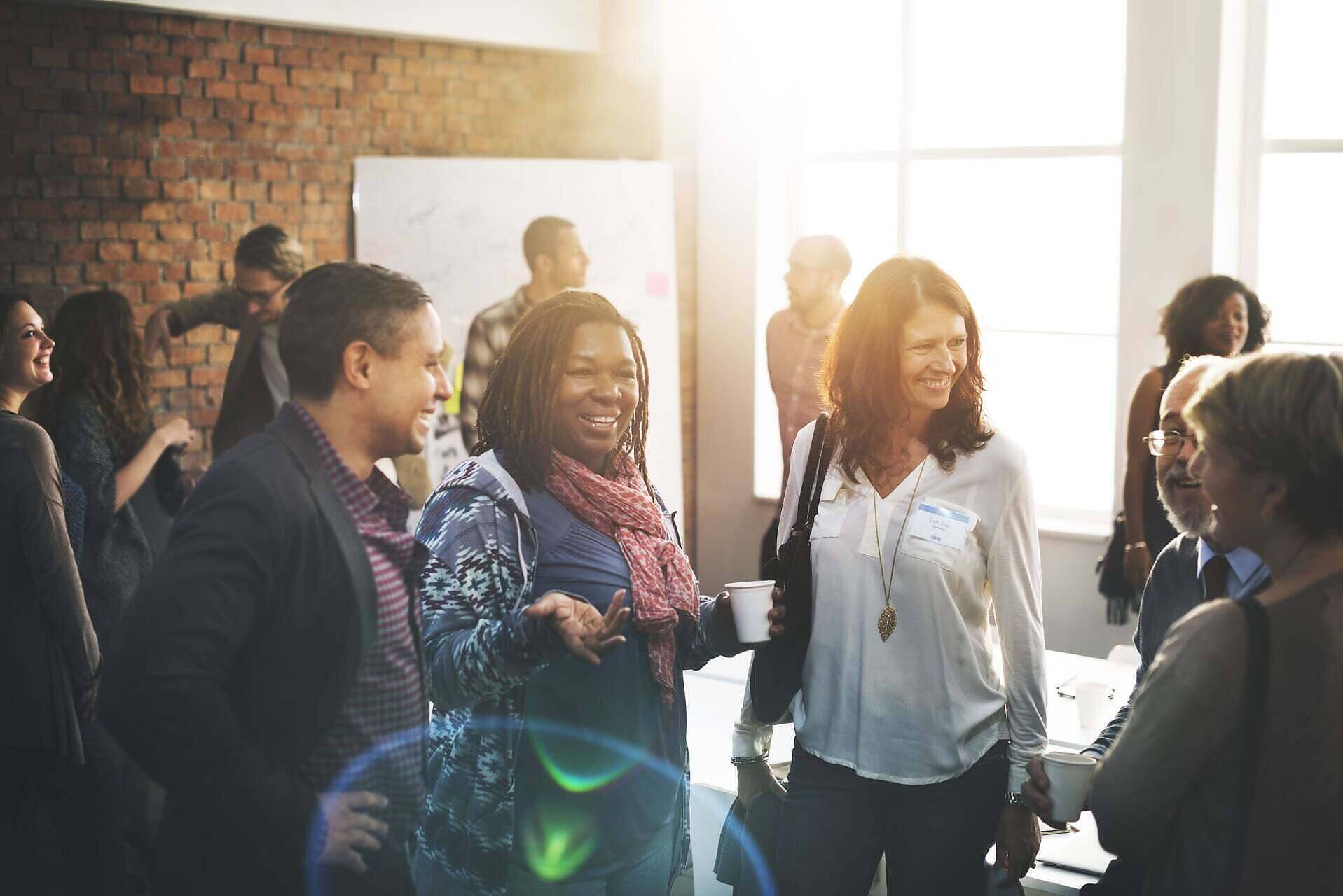 Diverse group of people smiling and interacting during a support meeting at an alcohol rehab center in Leicestershire