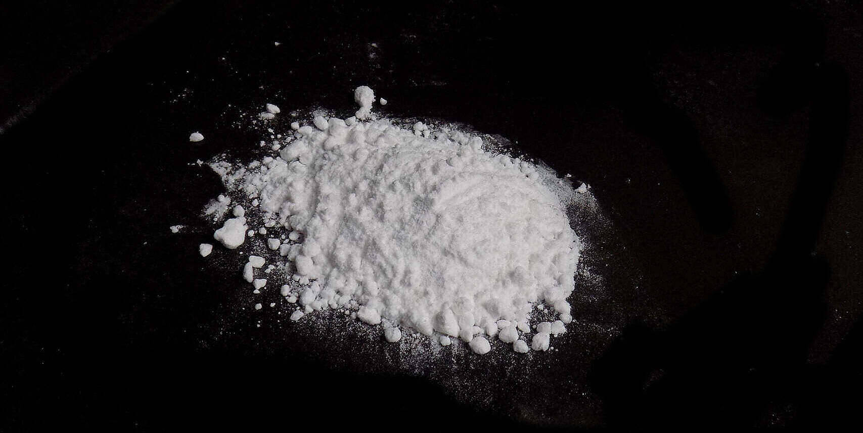 Close-up of white powdery substance resembling cocaine on a dark background, illustrating the stark reality of cocaine addiction