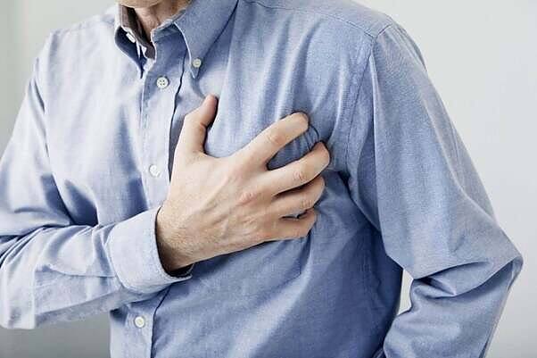 Man clutching chest, highlighting heart risks associated with mixing Viagra and cocaine.