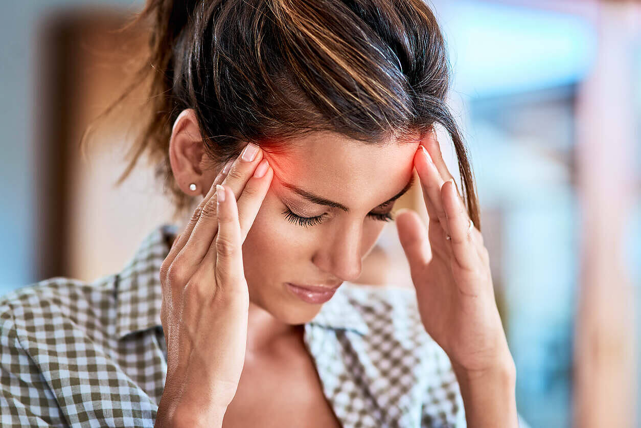 Young woman holding her head in pain, experiencing brain zaps as a withdrawal symptom during drug or alcohol detox