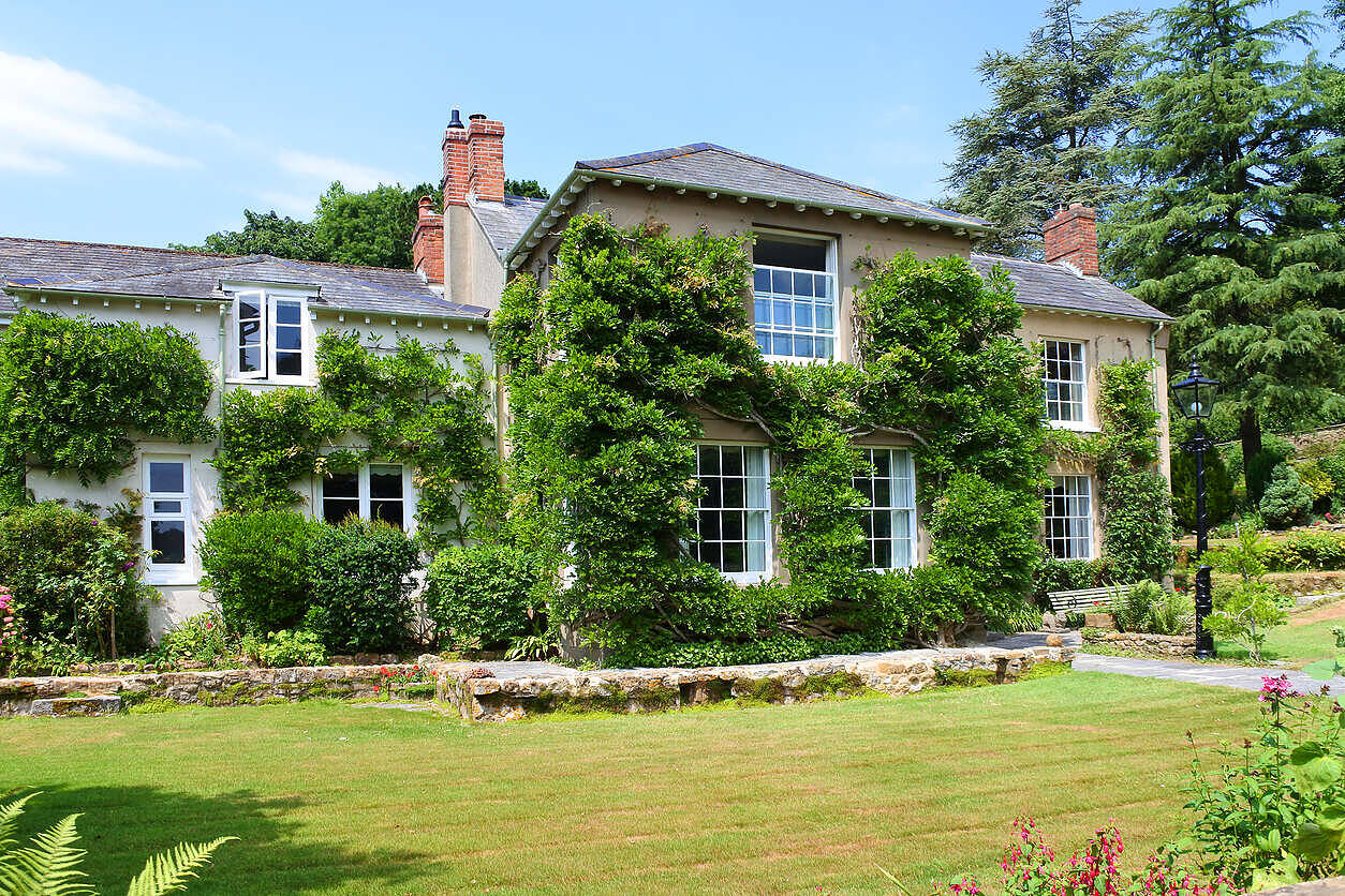 Charming English country house with ivy-covered walls, surrounded by lush gardens, ideal for alcohol rehabilitation in England