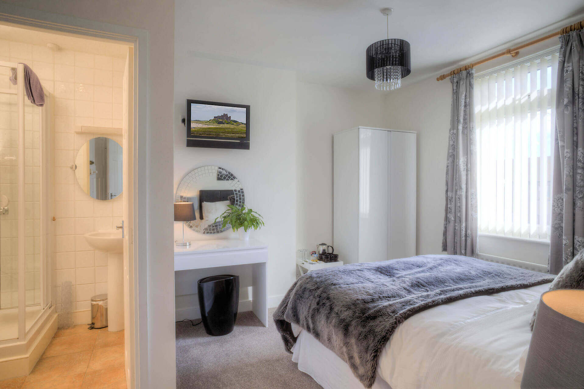 Cozy bedroom in Nottinghamshire alcohol rehabilitation facility featuring en-suite bathroom, TV, dressing table, and large windows, offering a welcoming environment for recovery