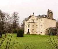 Elegant yellow manor house surrounded by manicured grounds and trees, ideal for peaceful addiction recovery