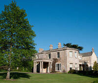 Elegant stone manor house with green lawns and trees, ideal for upscale rehab in Scotland