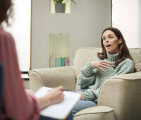 Woman in sweater gesturing while speaking to therapist during rehabilitation counseling session