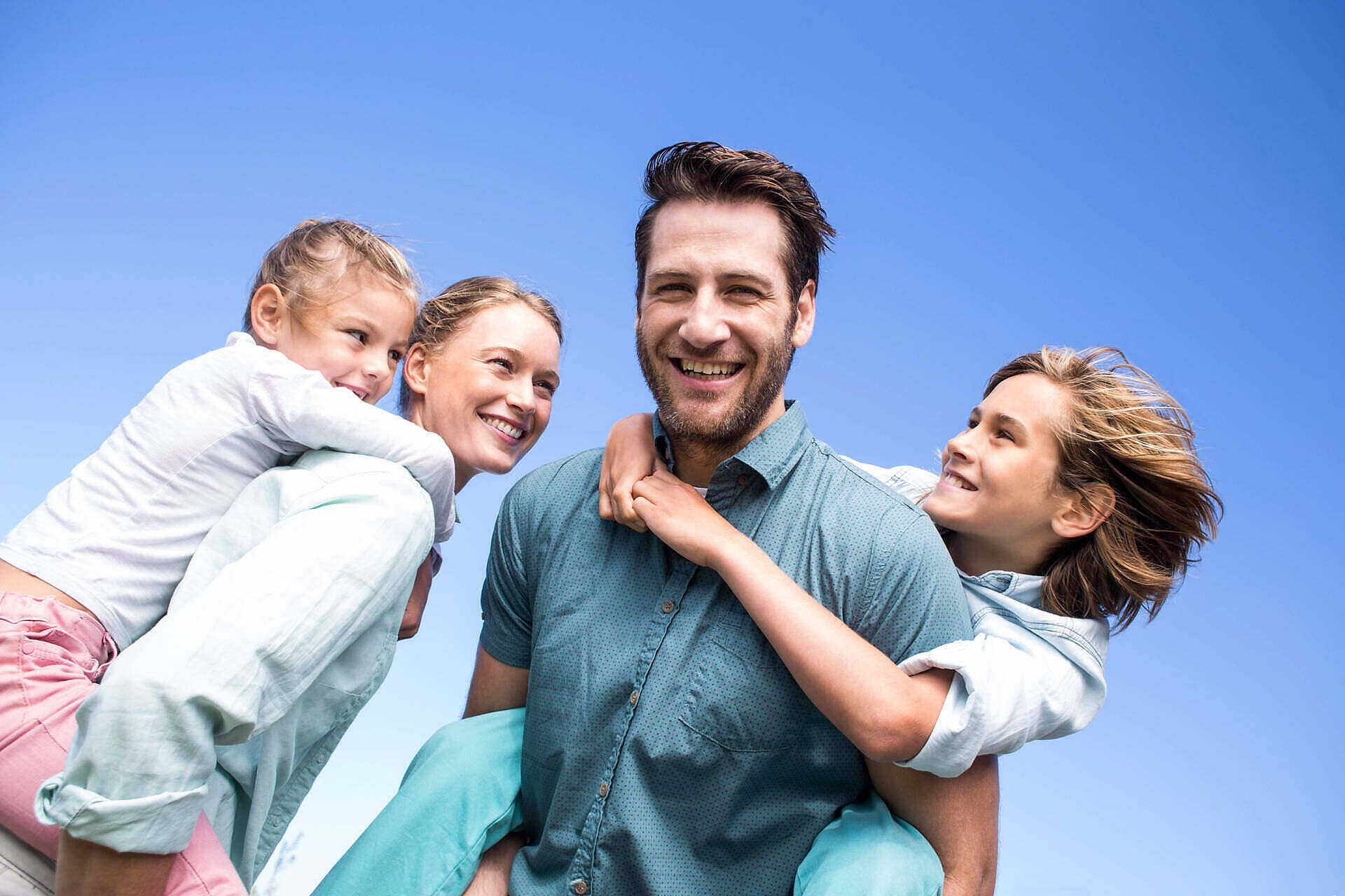 Happy family of four smiling outdoors, representing successful addiction recovery through rehab in Liverpool