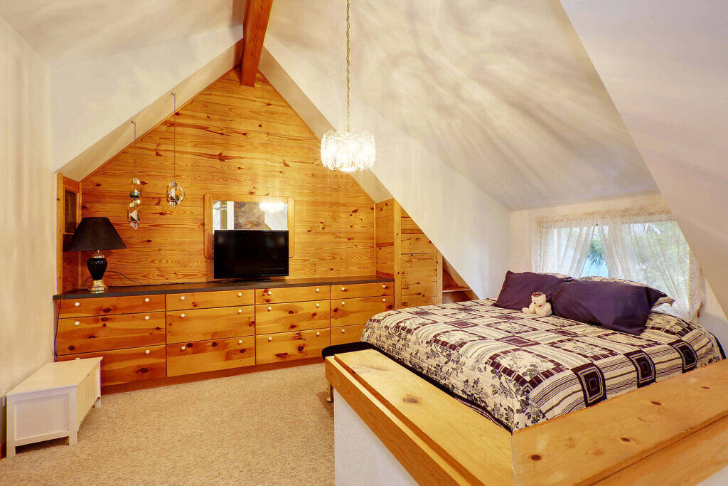 Cozy attic bedroom in a London alcohol detox facility, featuring wooden walls, plush bedding, and modern amenities for a comfortable recovery experience