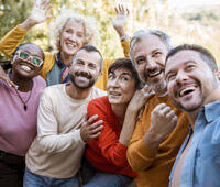 Diverse group of smiling people in colorful clothing embracing and celebrating, representing support and community in addiction recovery