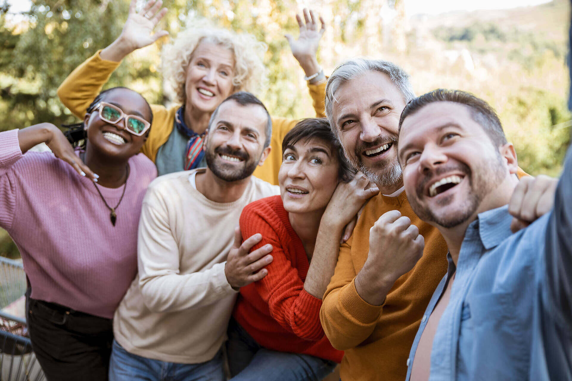 Diverse group of smiling people in colorful clothing embracing and celebrating, representing support and community in addiction recovery