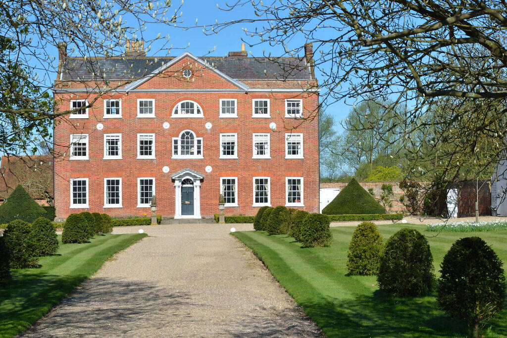 a brick building with a driveway and bushes