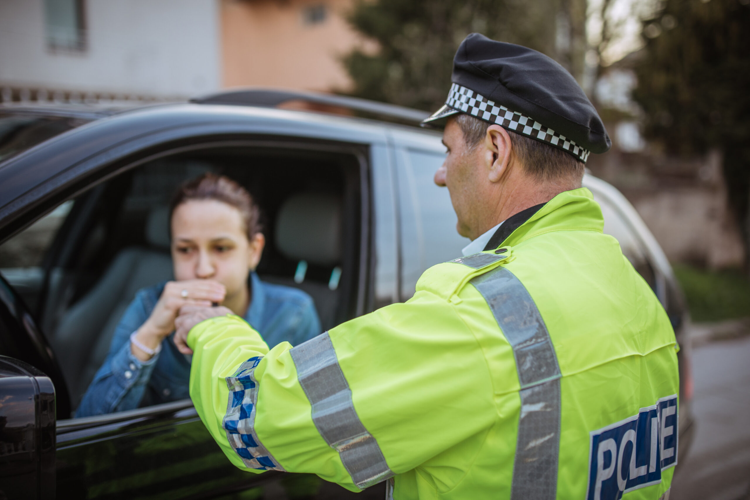 Police officer administering a roadside breath test to a female driver, illustrating drug and alcohol detection methods used by law enforcement