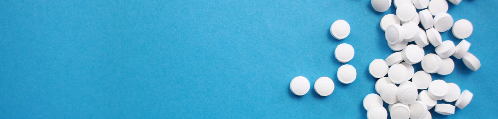 scattered percocet pills on a blue surface