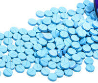 Blue Klonopin (Clonazepam) pills scattered from an open prescription bottle on a white background