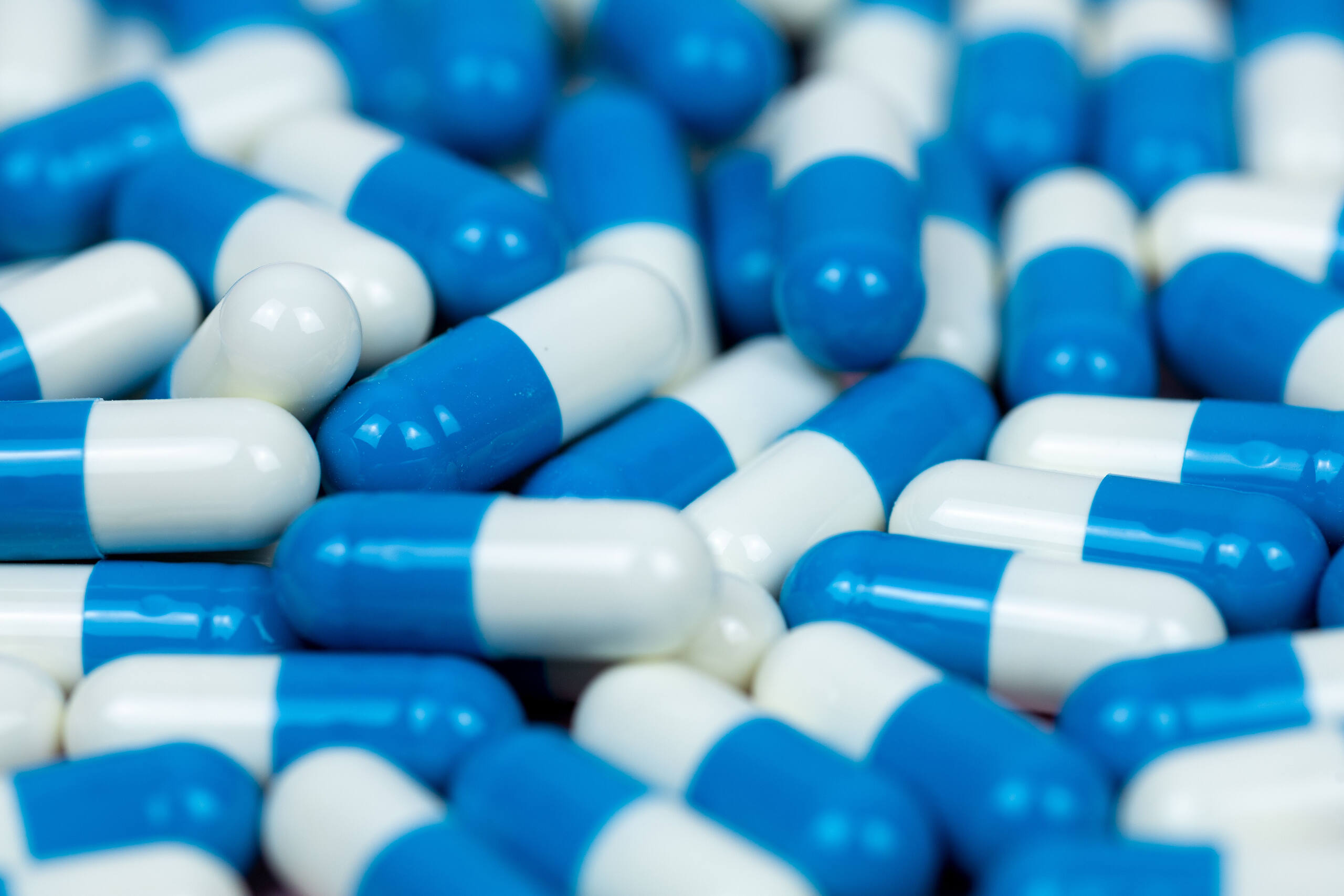 Close-up of blue and white prescription capsules, representing Vyvanse medication used to treat ADHD and potentially leading to addiction